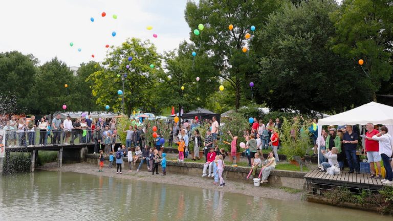 Besucherinnen und Besucher beim Familientag der FerienKultur Rechberghausen 2026 lassen im Landschaftspark Grüne Mitte bunte Luftballons steigen.