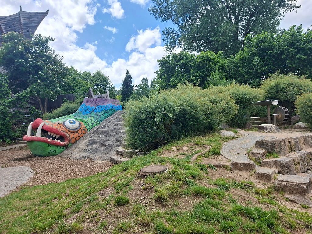 Bunter Spielbereich mit Drachenrutsche und Wasserspielelementen .