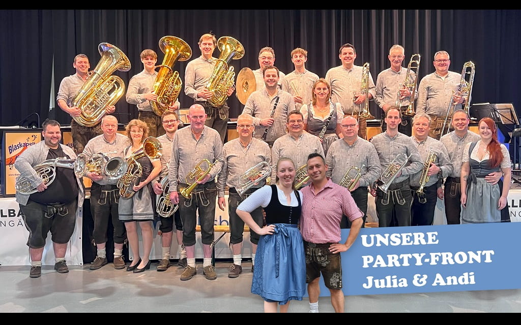 Blaskapelle Charivari mit Musikerinnen und Musikern sowie Party-Front Julia und Andi auf der Bühne.