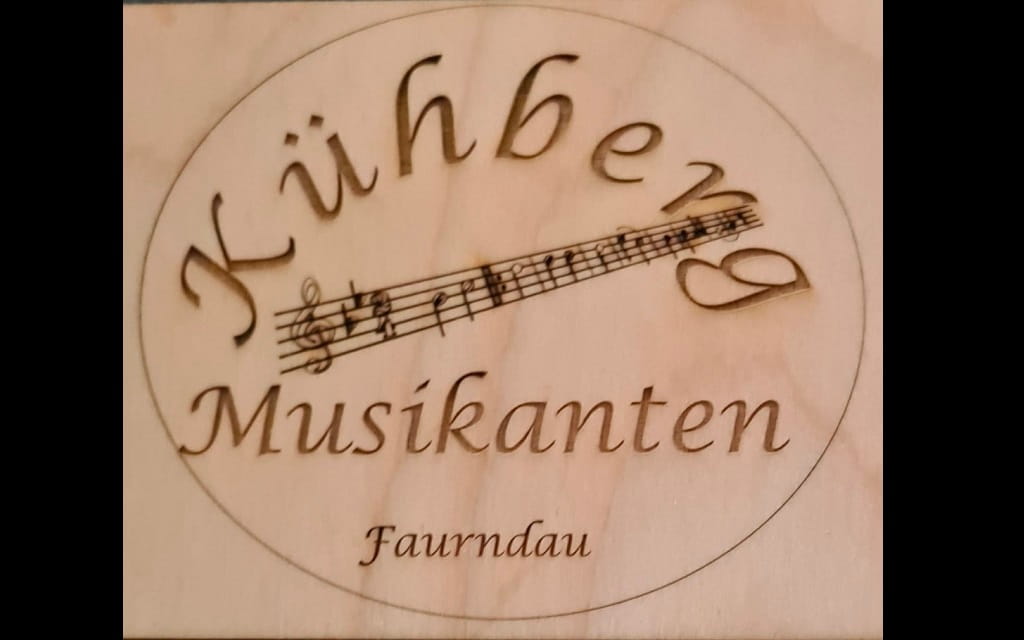 Logo der Kühberg Musikanten Faurndau mit Notenlinie und Schriftzug auf Holz.