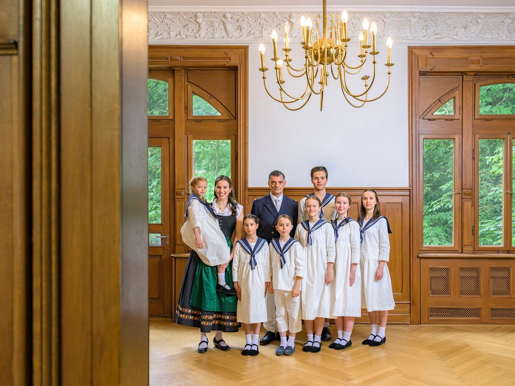 Maria, Kapitän von Trapp und die sieben Kinder der Familie von Trapp in einem festlichen Saal