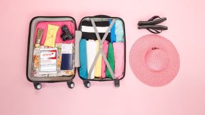 Geöffneter Reisekoffer mit Reiseutensilien, Tablet und prisma-Logo als Vorbereitung für das Bezahlen im Urlaub.