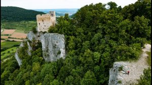 Blick auf die Burgruine Reußenstein auf einem Felsen am Albtrauf, umgeben von dichtem Wald und weiter Landschaft.