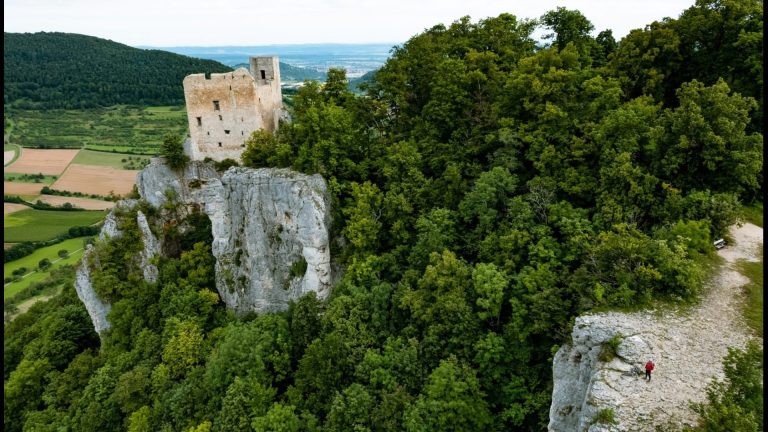 Blick auf die Burgruine Reußenstein auf einem Felsen am Albtrauf, umgeben von dichtem Wald und weiter Landschaft.