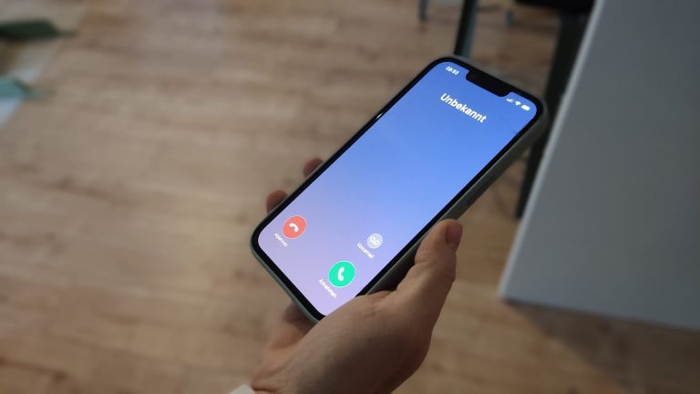 Eine Person hält ein Smartphone mit einem eingehenden Anruf von einer unbekannten Nummer in der Hand. Solche Anrufe können Teil von Betrugsmaschen sein.
