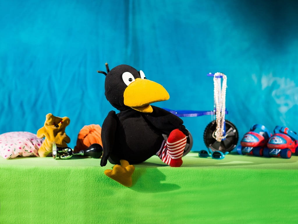 Kleiner Rabe Socke als Spielfigur vor buntem Bühnenbild