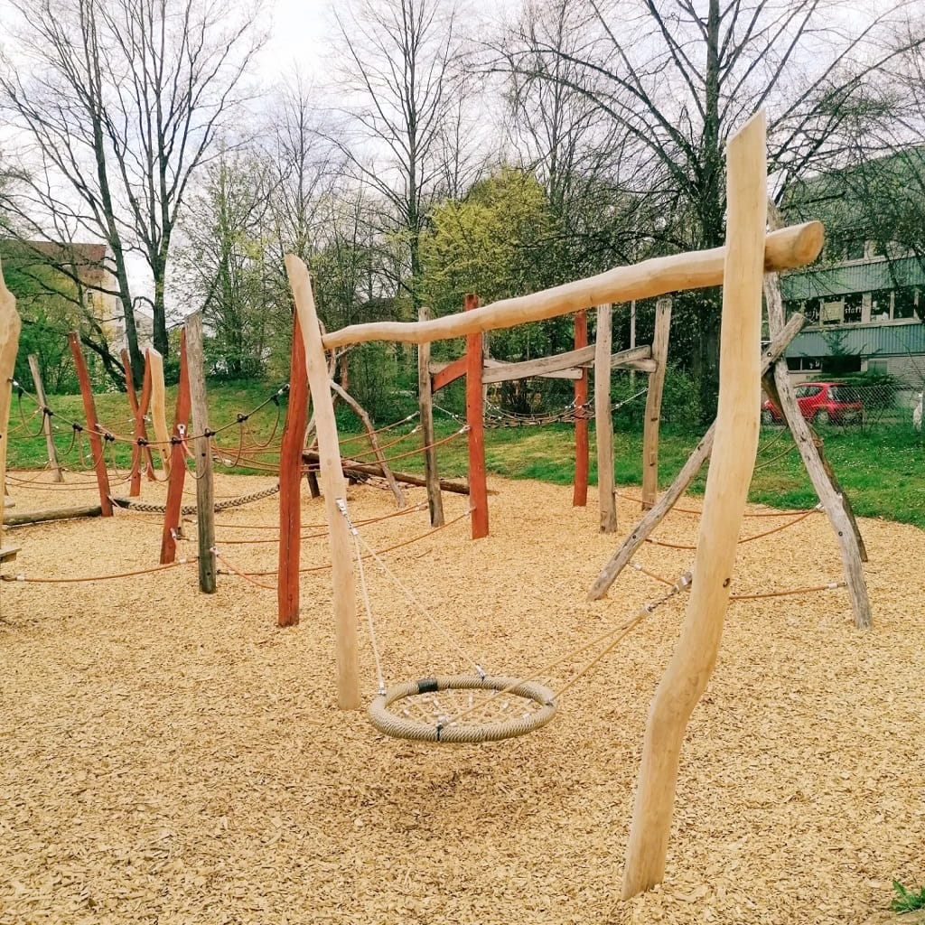 Spielplatz in der Dürerstraße in Göppingen mit einer Nestschaukel und verschiedenen Kletter- und Balanciermöglichkeiten aus Holz.