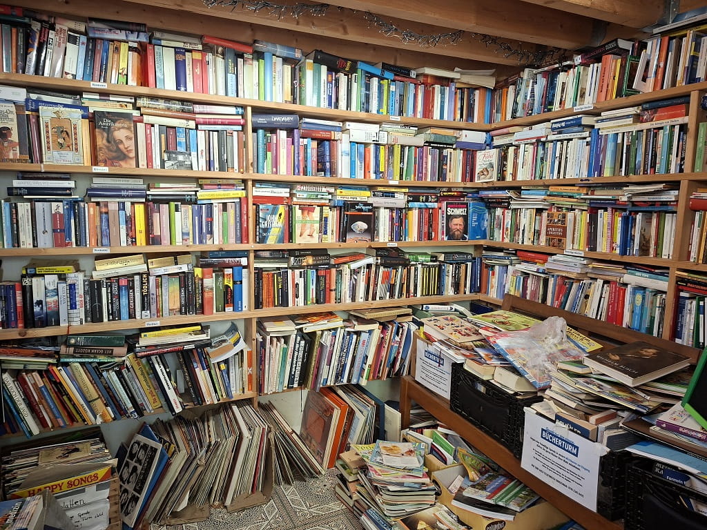 Dicht gefüllte Bücherregale mit Romanen, Sachbüchern und weiteren Medien im Inneren des blauen Bücherturms in Dürnau.