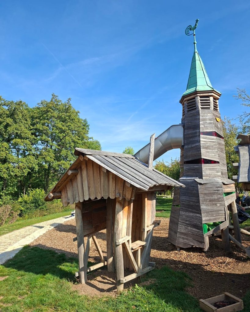 Hölzerner Abenteuerspielplatz mit Turm und Rutsche.
