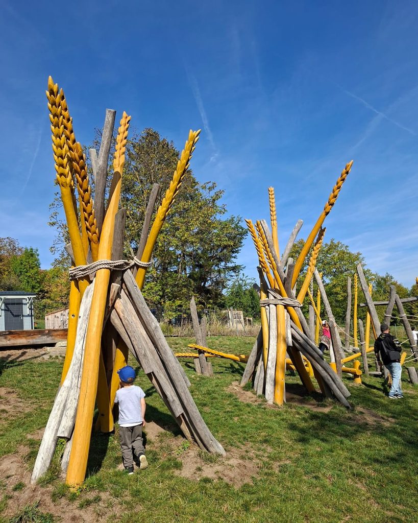 Kind auf dem Spielplatz mit großen hölzernen Getreideähren im Freilichtmuseum Beuren