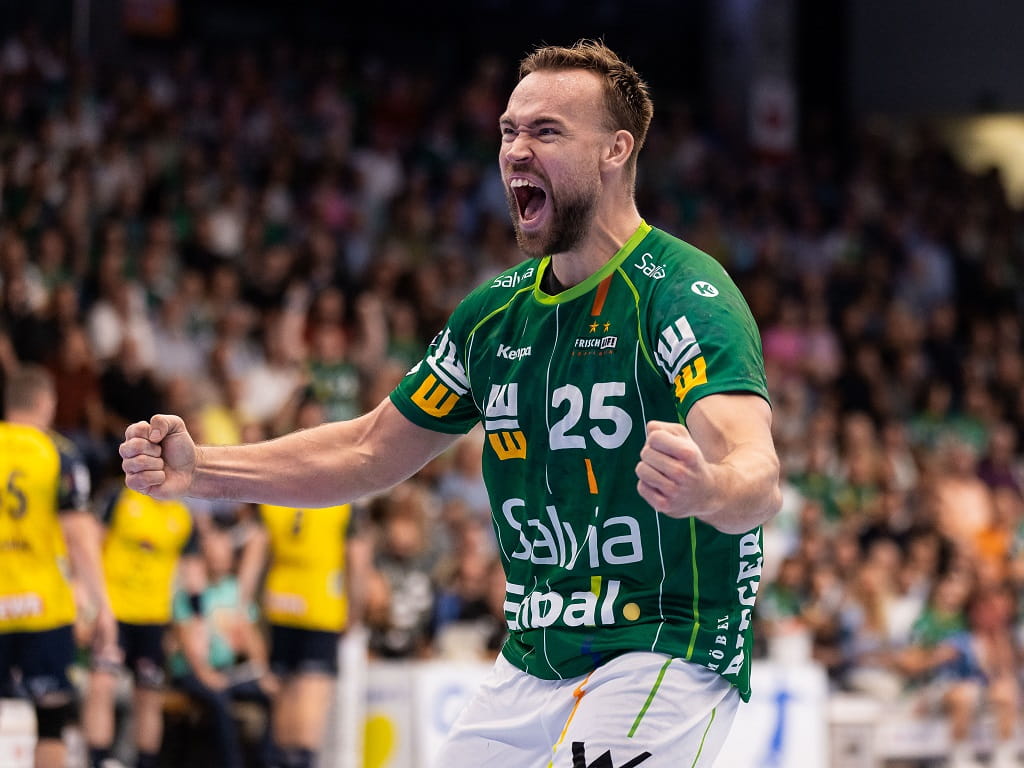 Jubelnder Handballspieler von FRISCH AUF! Göppingen im grünen Trikot mit der Nummer 25, geballten Fäusten und weit geöffnetem Mund.