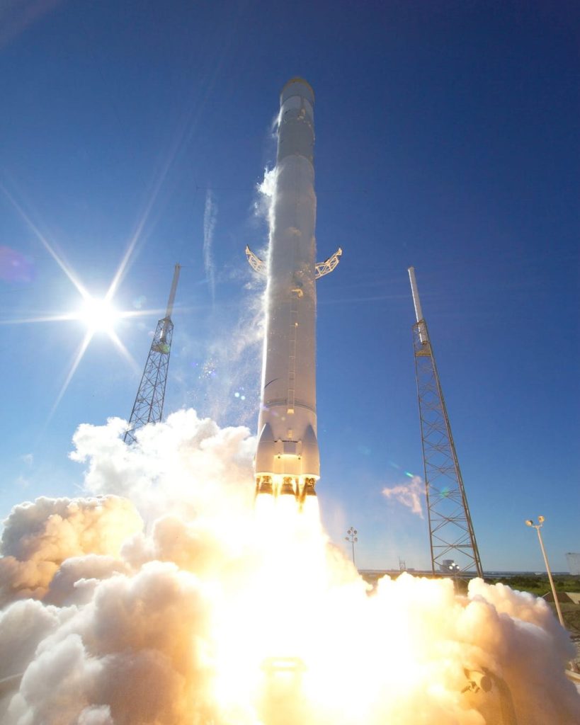 Raketenstart unter blauem Himmel mit heller Flamme und dichter Rauchwolke