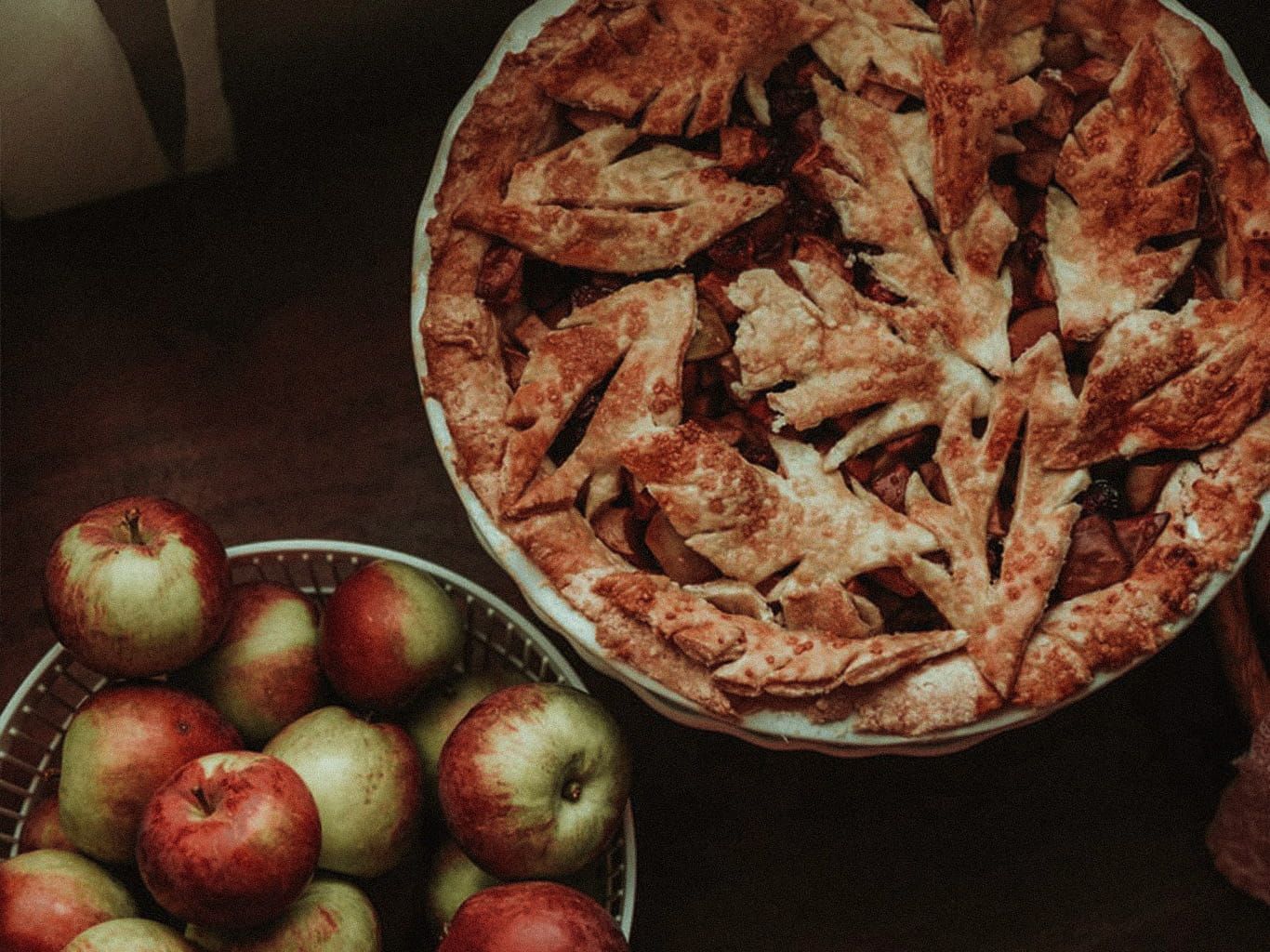 Selbstgemachter Ofenschlupfer sowie eine Schüssel voller Äpfel stehen auf einem Tisch